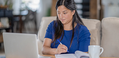 Woman taking notes in front of a computer