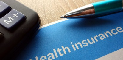 A calculator, pen, and a health insurance document on a table.